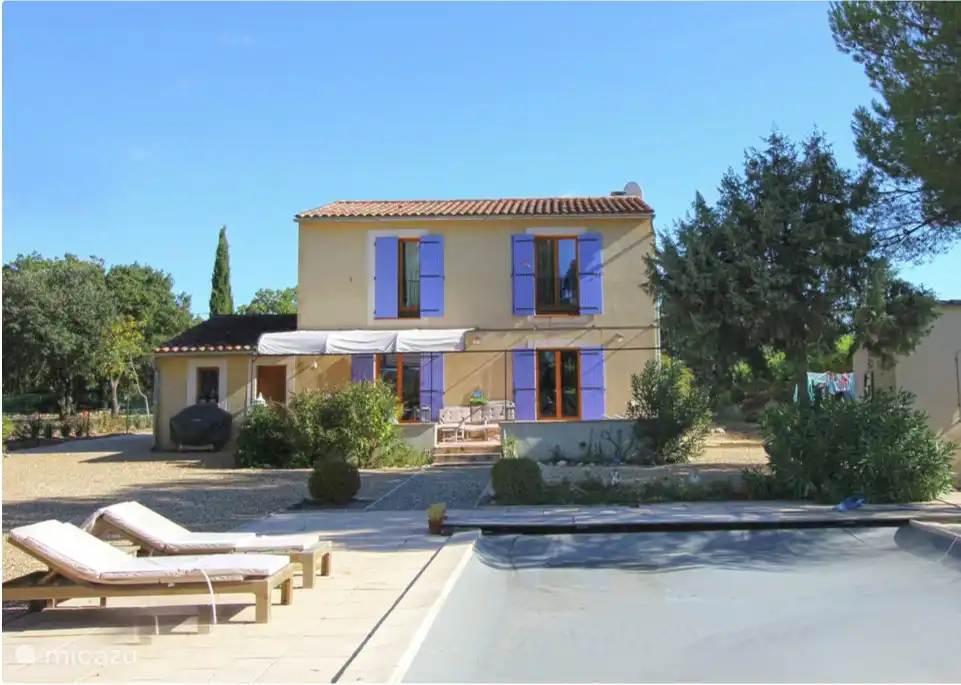 Parte trasera con persianas lavanda y hermosa terraza parcialmente cubierta con muebles de jard&#237;n y cojines