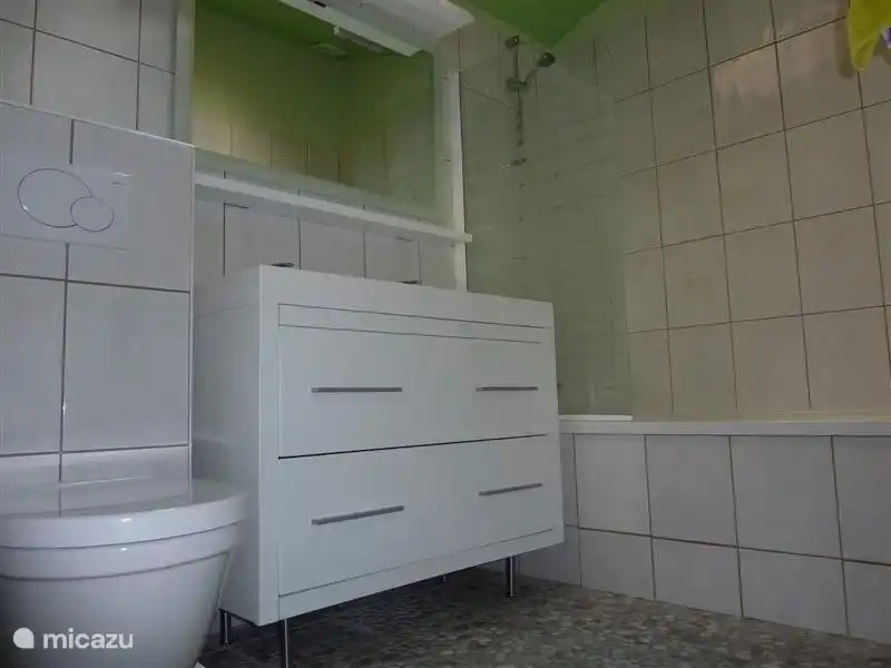 Salle de bain au rez-de-chaussée avec baignoire, douche dans la baignoire, double vasque et toilettes.Tomettes au sol très particulières avec pierres de rivière, même ambiance que les terrasses.