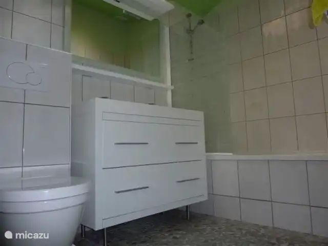 Village le Chat, Maison Meermin | France, Charente, Écuras - maison de vacances Salle de bain au rez-de-chaussée avec baignoire, douche dans la baignoire, double vasque et toilettes.Tomettes au sol très particulières avec pierres de rivière, même ambiance que les terrasses.