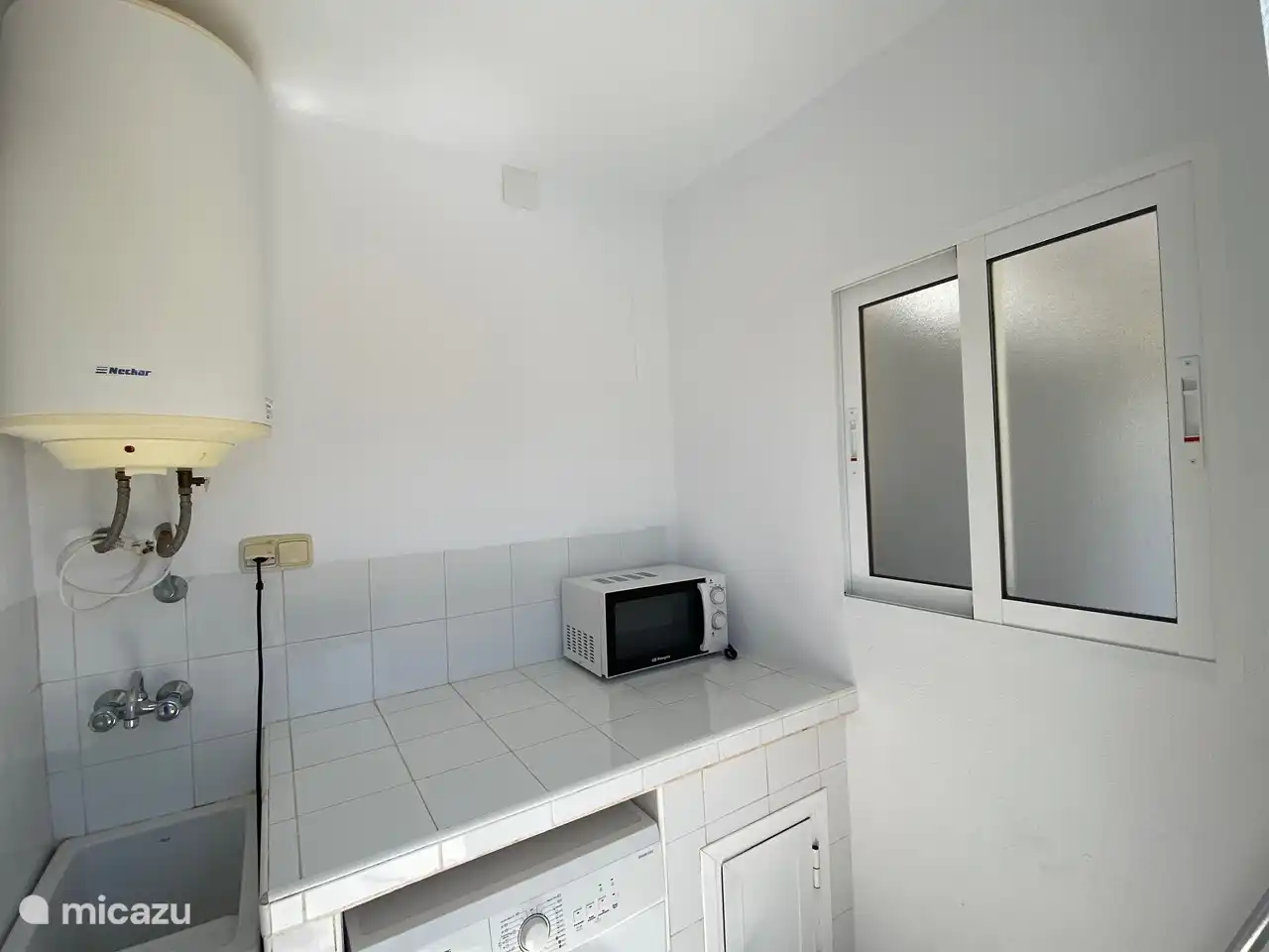 Nouvelle buanderie de Casa Mirador avec salle de douche séparée, lave-linge, évier, chauffe-eau, kitchenette et micro-ondes.