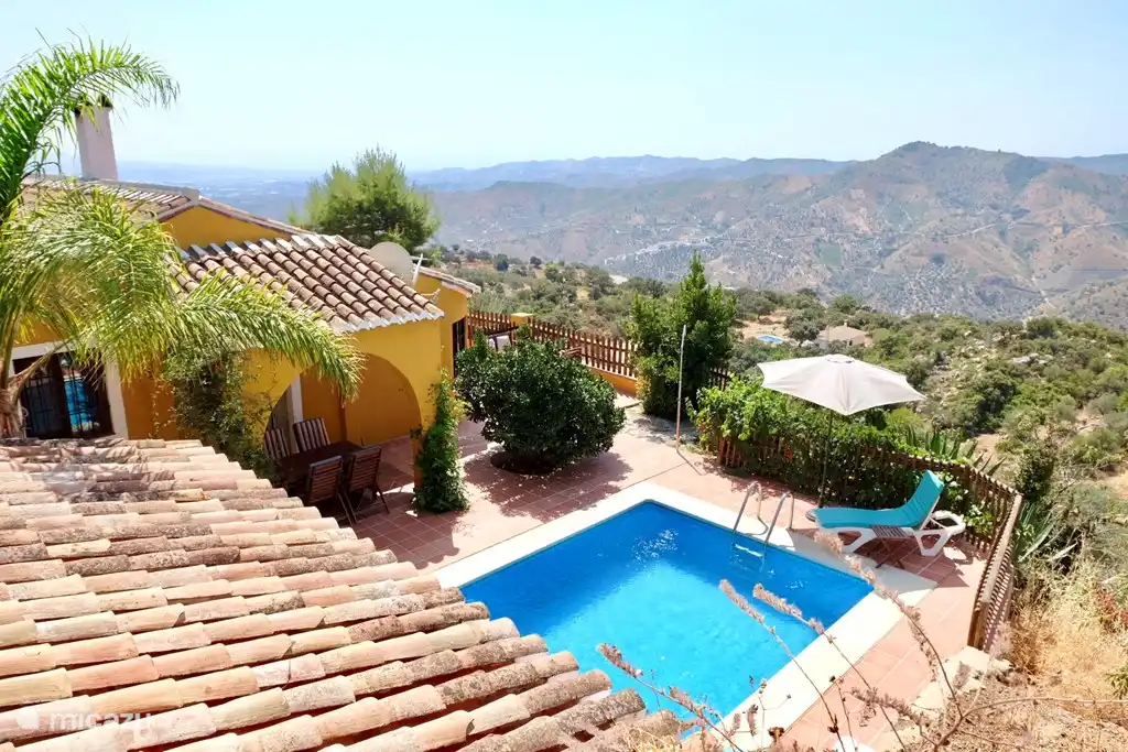 Overzicht van zwembad en terrein naast de villa. Op deze foto niet te zien, maar je ziet de zee!