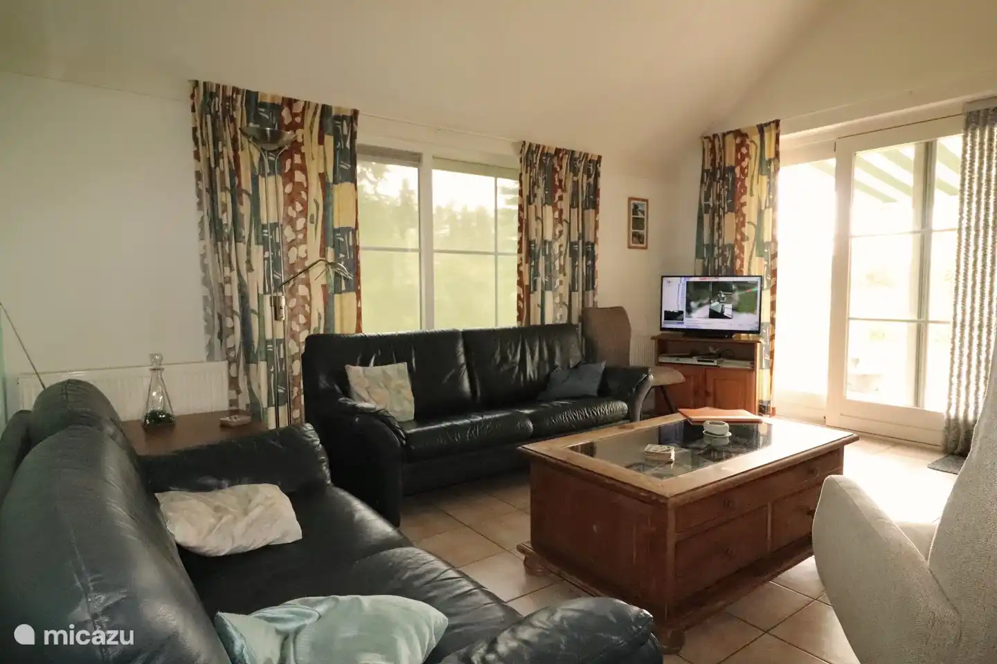 Helles Wohnzimmer. Ledersofa und Couchtisch mit vielen Informationen zu (Freizeit-) Optionen. Gratis Wifi. Fliesenboden. Über Schiebetür zur Sonnenterrasse auf S / W. Sonnenschutz-Seitenfenster, Sonnenschirm Terrasse-Seite.