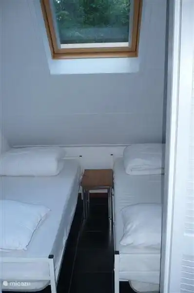 Dieser zusätzliche Schlafraum wurde im Erdgeschoss geschaffen. Es gibt zwei Einzelbetten, die durch einen engen Durchgang voneinander getrennt sind. Von Ihrem Bett aus können Sie den Blick auf die Bäume genießen und Sie werden zum Schlafen gerockt. Sie können das Rollo jedoch auch schließen.