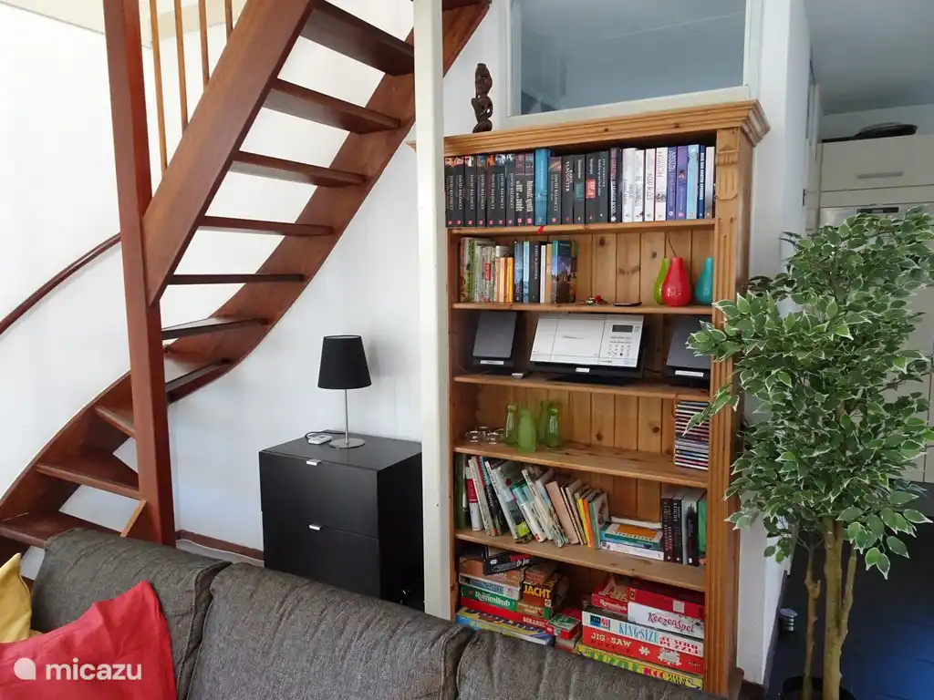 Das Bücherregal mit vielen Spielen, informativen Naturbüchern und Kochbüchern. Links die Treppe ins Obergeschoss.